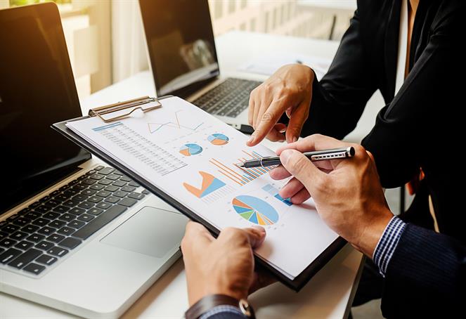 Serious middle aged businessman presenting company business goals to colleagues during meeting in boardroom, male coach training workers, explaining successful strategies on flipchart during briefing